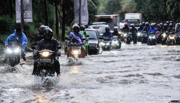 People ride motorcycles along a flooded street in Bekasi, near Jakarta, Indonesia