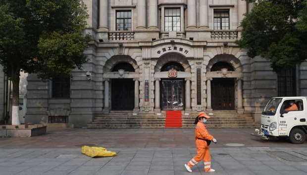 A sanitation worker wearing a face mask walks past a branch of Industrial and Commercial Bank of China (ICBC) in Wuhan, the epicentre of the novel coronavirus outbreak, Hubei province, China