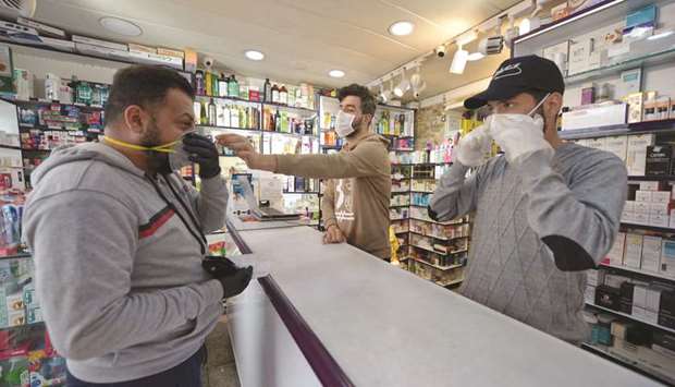 An Iraqi man checks a protective mask at a pharmacy yesterday, in the holy city of Najaf.