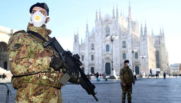 Military officers wearing face masks stand outside Duomo cathedral, closed by authorities due to a coronavirus outbreak, in Milan, Italy