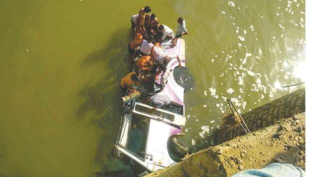 People try to rescue passengers after a bus ferrying a wedding party fell while crossing a bridge yesterday.