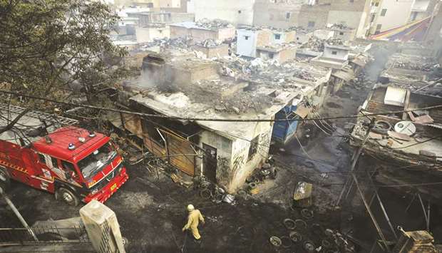 A firefighter walks past damaged shops at a tyre market after they were set on fire by a mob in New Delhi, yesterday.