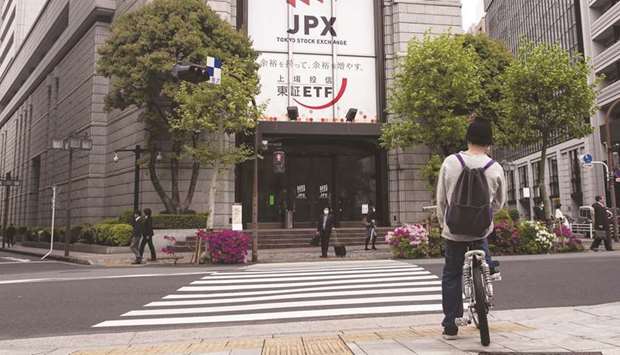 A cyclist sits on a bicycle at a crossing in front of the Tokyo Stock Exchange. The TSE dived 2.1% to 21,948.23 points yesterday.