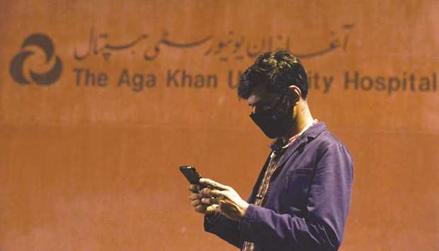 A journalist uses his cellphone outside Karachiu2019s Aga Khan University Hospital, where a Covid-19 patient has been admitted.