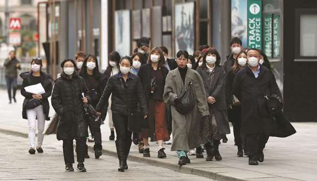 Tourists wearing protective masks walk near Duomo square, as a coronavirus outbreak continues to grow in northern Italy, in Milan yesterday.