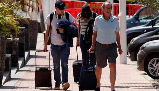 Tourists leave by foot the H10 Costa Adeje Palace hotel, which was placed on lockdown after four cases of the coronavirus were detected there, but others showed no symptom of illness, in Adeje, on the Spanish island of Tenerife, Spain