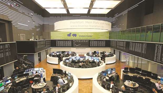 Traders work in front of a board displaying the chart of Germanyu2019s share index DAX at the Frankfurt Stock Exchange. The DAX 30 slumped 3.9% to 11,890.35 points yesterday over fears the coronavirus could wreak havoc on the world economy.