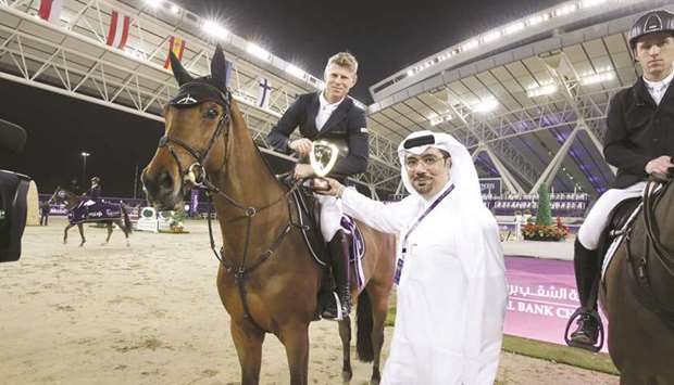 Hussein Ali al-Abdulla (right), EGM & Chief Marketing Officer of Commercial Bank, presents the trophy to Julien Epaillard, after the Frenchman won the  CSI5* 1.55m class aboard Virtuose Champeix on the second day of the Commercial Bank CHI Al Shaqab Presented by Longines.