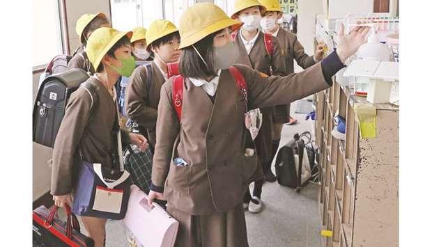 Elementary schoolchildren disinfect their hands before leaving school in Osaka.
