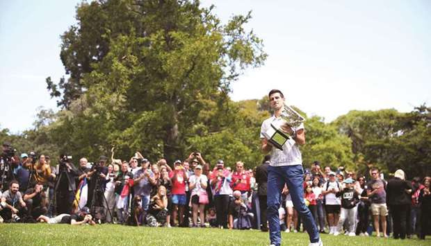Australian Open champion Serbiau2019s Novak Djokovic poses with the trophy during a photo shoot at the Royal Botanic Gardens Victoria yesterday. (Reuters)