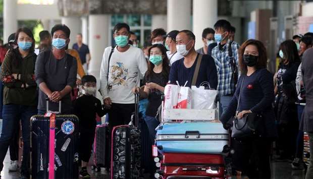 Passengers wearing medical masks walk at the international arrivals terminal