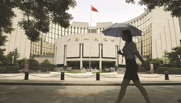 A pedestrian walks past the Peopleu2019s Bank of China headquarters in Beijing. The PBoC injected 1.7tn yuan ($242.74bn) via reverse repos earlier this week to shore up confidence and cut some key money market interest rates.