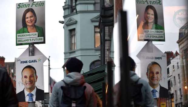 Pedestrians walk past campaign posters featuring Sinn Fein President Mary Lou McDonald and also Ireland's Prime Minister and leader of the Fine Gael party, Leo Varadkar as they walk along a street in Dublin