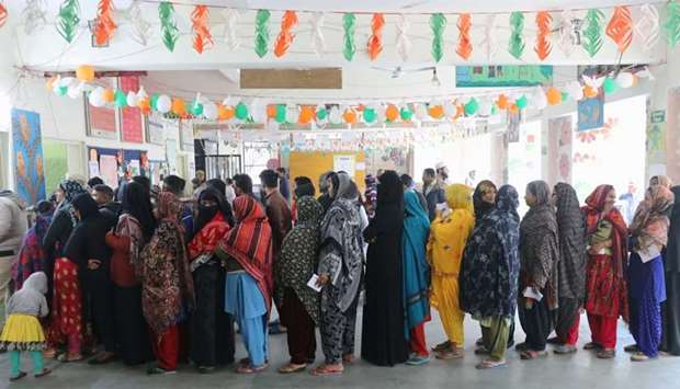 Voters stand in queues as they wait to cast their vote outside a polling booth during the state assembly election in New Delhi