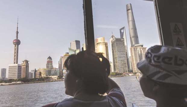 Passengers look out at the skyscrapers of the Pudong Lujiazui Financial District while taking a ferry across the Huangpu River in Shanghai. The Chinese economy will sputter towards normal soon after the coronavirus outbreak forced an extended holiday, although numerous stores and factories will remain shut and many white collar employees will continue working from home.