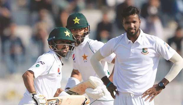 Pakistanu2019s Babar Azam (left) and Shan Masood (centre) run between the wickets as Bangladeshu2019s Ebadat Hossain looks on during the second day of the first Test in Rawalpindi, Pakistan, yesterday. (AFP)