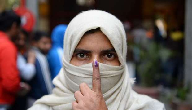 A woman shows her ink-marked finger after casting her vote at a polling station during the Legislative Assembly elections in New Delhi