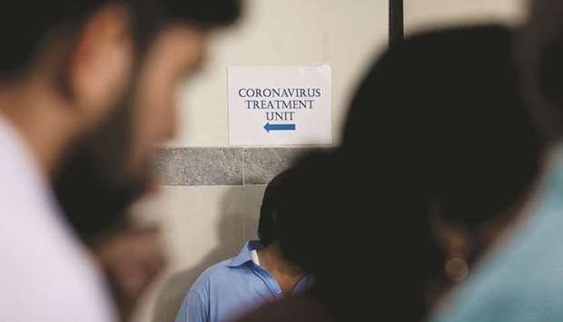 This picture taken earlier this month shows people walking past a notice pointing the direction of an isolation section, set up for the precautionary measures for the coronavirus patients treatment, at the Jinnah Post Graduate Medical Centre (JPMC) in Karachi.