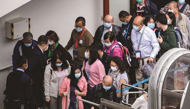 Passengers queue up to finally disembark from the World Dream cruise ship at the Kai Tak cruise terminal in Hong Kong yesterday where 3,600 people had remained confined aboard for days as authorities conducted health checks due to the outbreak of the new coronavirus in mainland China.