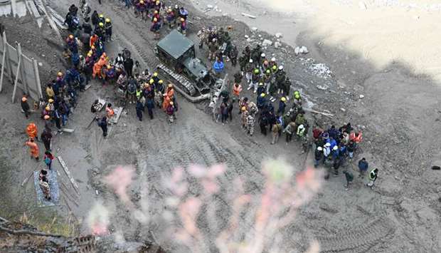 Rescue teams gather near the entrance of a tunnel blocked with mud and debris, where workers are trapped, in Tapovan of Chamoli district