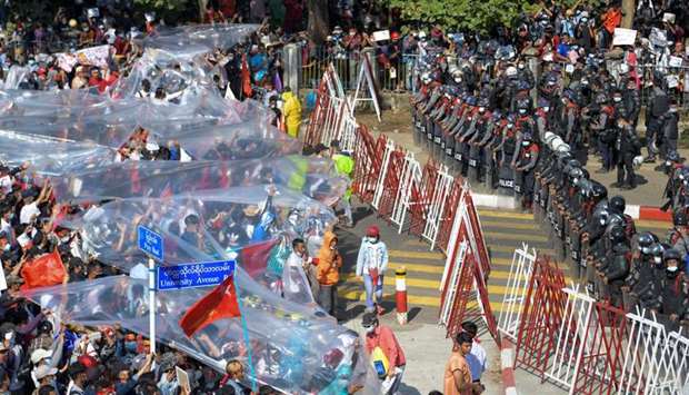 People cover with plastic in case of a water canon use during a rally against the military coup and to demand the release of elected leader, in Yangon, Myanmar