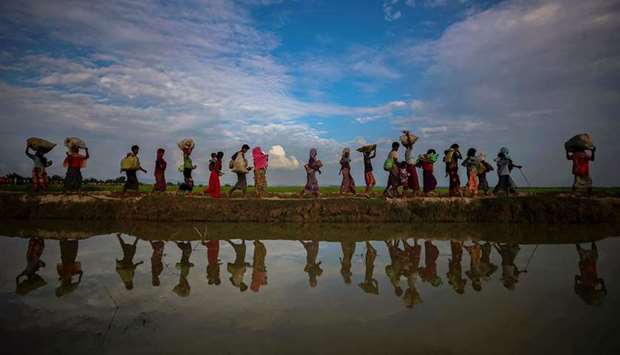 Rohingya refugees are reflected in rain water along an embankment next to paddy fields after fleeing from Myanmar into Palang Khali, near Cox's Bazar, Bangladesh November 2, 2017. REUTERS