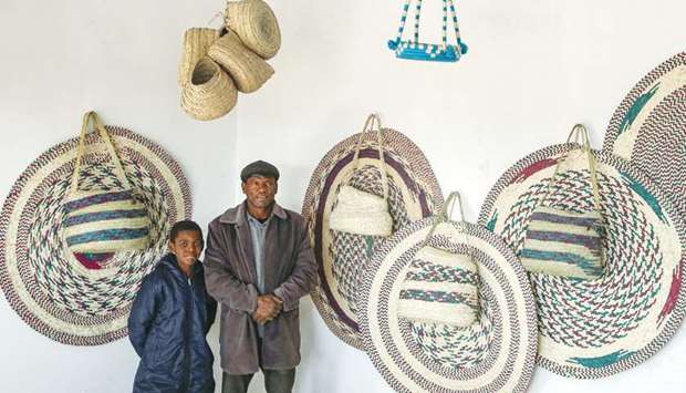 A man and boy pose for a picture next to palm wicker products on display, made by Halima Mohamed.