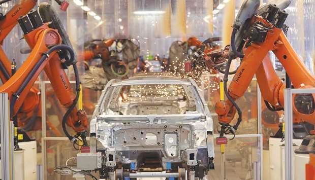 Robotic arms work on a Volkswagen Passat chassis on the production line inside a VW factory in Emden, Germany (file). Factories across parts of Europe, as well as in China and Japan, struggled as renewed lockdown measures alongside supply shortages hurt activity, surveys showed.
