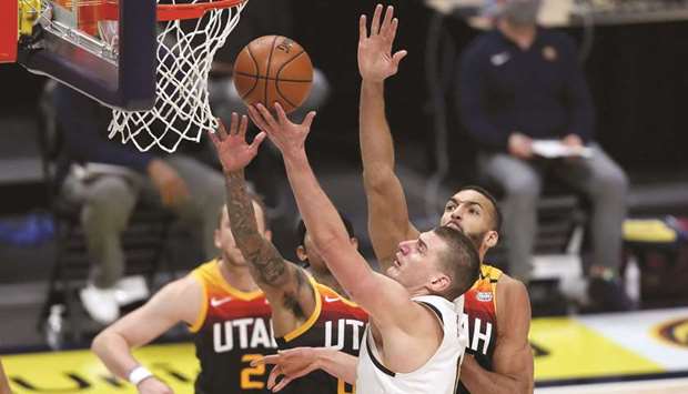 Nikola Jokic (R) of the Denver Nuggets goes to the basket against Joe Ingles, Jordan Clarkson and Rudy Gobert of the Utah Jazz in the third quarter of their game in Denver,  Colorado.