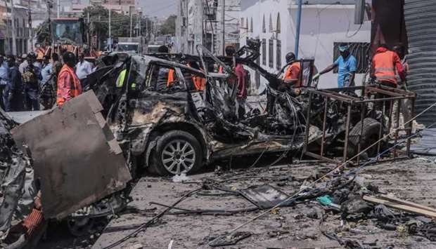 Rescue personnel and bystanders gather near debris at the site of a suicide car bombing attack near a security checkpoint in Mogadishu