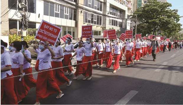 Nurses hold up signs as they march in a demonstration against the military coup in Yangon yesterday.
