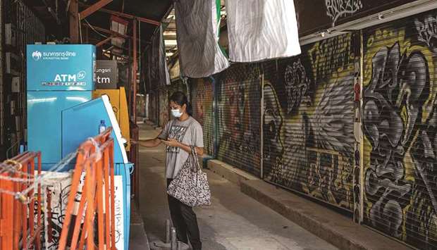 A woman withdraws money from an ATM on Khao San Road in Bangkok. Thailandu2019s pandemic-shattered economy suffered its worst full-year performance in more than two decades, data showed yesterday.