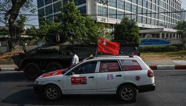 A car decorated to support the National League for Democracy (NLD) drives past a military vehicle parked along a street in downtown Yangon, the morning after Myanmar's military cut the nation's internet and deployed extra troops around the country