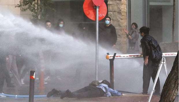 This picture taken on Saturday shows a protester on the ground after she was sprayed with a water cannon during a rally against corruption and Covid-19 restriction measures in Nicosia.