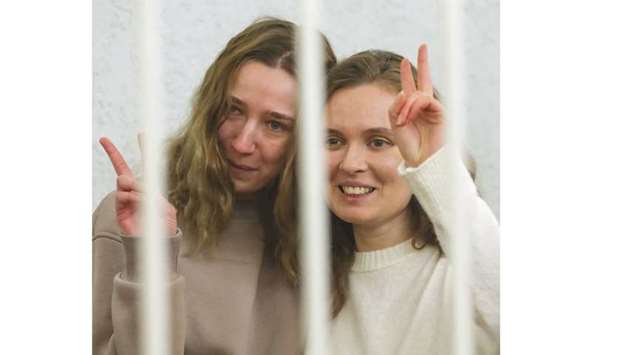 Andreyeva and Chultsova (left) flash the victory sign inside a defendantsu2019 cage during a court hearing in Minsk.