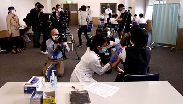 Members of the media look on as a medical worker (R) receives a dose of the coronavirus disease (Covid-19) vaccine as Japan launches its inoculation campaign, at Tokyo Medical Center in Tokyo