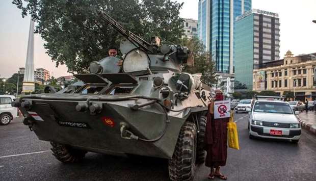 A Buddhist monk holding a sign stands next to an armoured vehicle during a protest against the military coup, in Yangon, Myanmar
