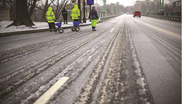 City workers spread chemical salt yesterday on an icy William Howard Taft Bridge in the Woodley Park neighbourhood of Washington, DC.