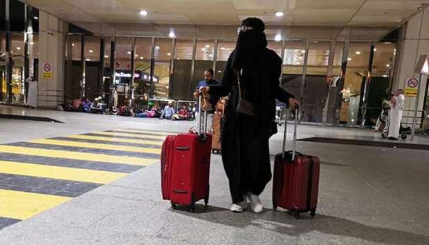 A Saudi woman walks with her luggage as she arrives at King Fahd International Airport in Dammam, Sa