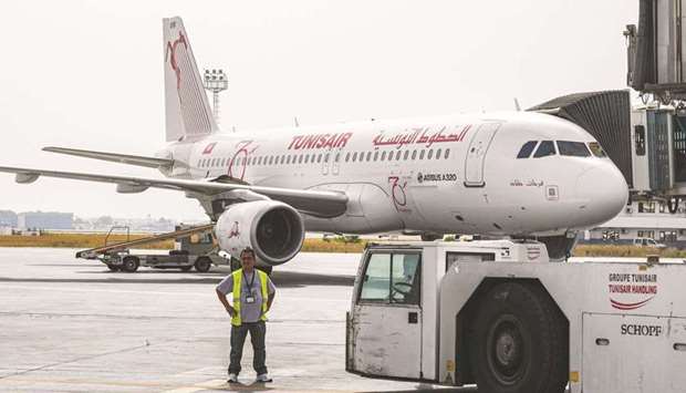 A worker of Tunis-Carthage International Airport stands near a TunisAir Airbus A320 aircraft on the tarmac at the airport in the Tunisian capital (file). The state-owned airline is heavily indebted and subsidised by the public purse.