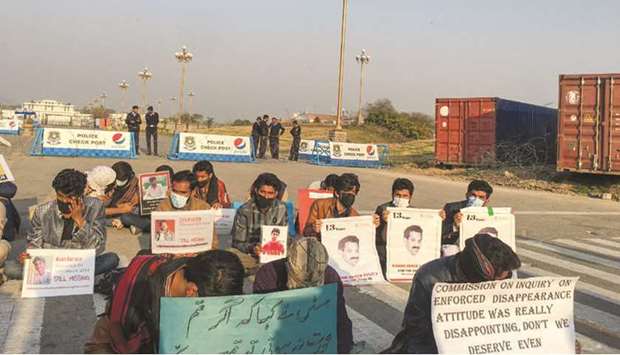 People hold signs and photos during a protest in Islamabad to demand information on the whereabouts of their missing family members.
