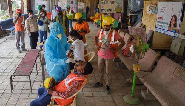 A health worker wearing protective gear takes a swab sample of a labourer for a Covid-19 coronavirus test at a construction site, in Mumbai 