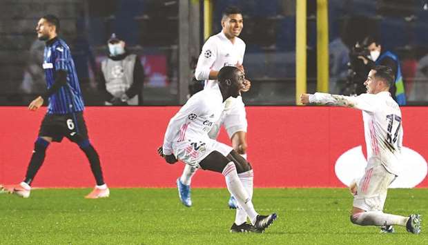 Real Madridu2019s French defender Ferland Mendy (left) celebrates with teammates Lucas Vazquez (right) and Casemiro after scoring against Atalanta during the UEFA Champions League round of 16 first leg match in Bergamo, Italy. (AFP)