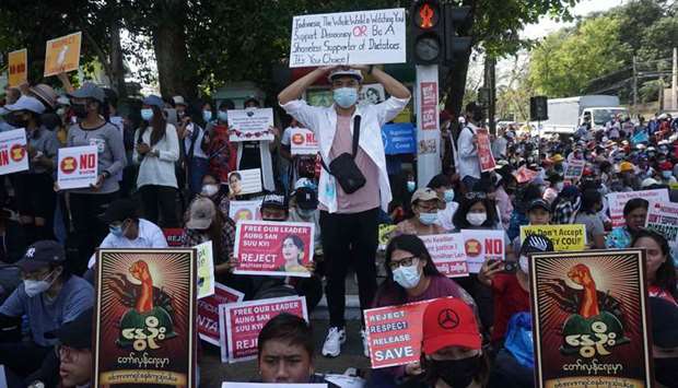 Protesters hold signs as they take part in a demonstration against the military coup in Yangon