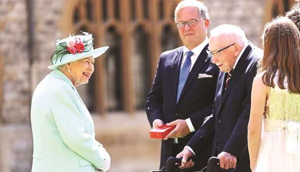 This file photo taken on July 17 last year shows Queen Elizabeth speaking with Captain Moore and his family during an investiture to confer the Honour of Knighthood upon him at Windsor Castle in Windsor, west of London.