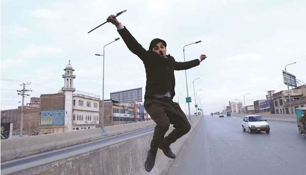 Usman Khan, 29, dressed up as Charlie Chaplin, performs along a street in Peshawar.