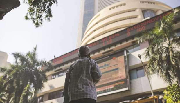 A man looks up at a screen and an electronic ticker board outside the Bombay Stock Exchange building in Mumbai. Having propelled the benchmark gauge almost 10% last week in a budget-driven rally, stock bulls in India are now counting on earnings to be the catalyst for the next leg up.