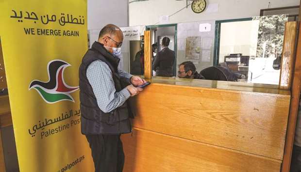 A man is assisted at a post office in the city of Al-Bireh, about 15 kilometres north of Jerusalem in the occupied West Bank, yesterday.