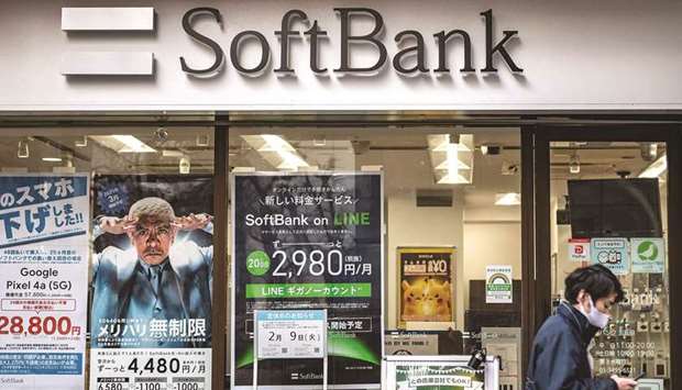 A pedestrian walks past a shop of SoftBank Group along a street in Tokyo yesterday. SoftBank reported a record profit in its Vision Fund as a surging stock market lifted the value of its portfolio companies.
