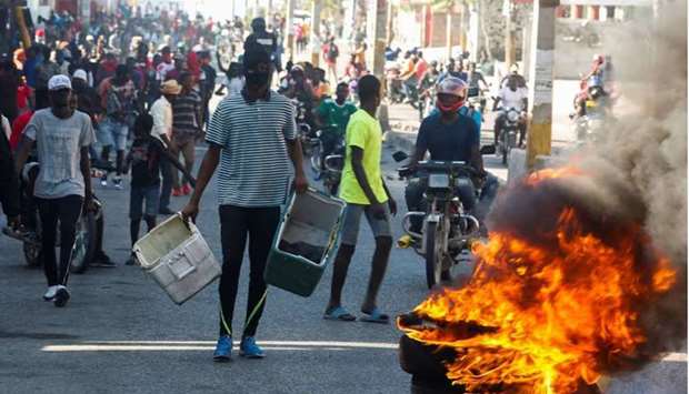Demonstrators gather behind a burning barricade during protests against Haiti's President Jovenel Moise, in Port-au-Prince, Haiti